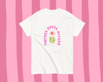 May include: White t-shirt featuring a pink and orange flower design with the words "NURTURE QUEER NATURE" in pink, arched above and below the flower. The shirt has short sleeves and a crew neck.