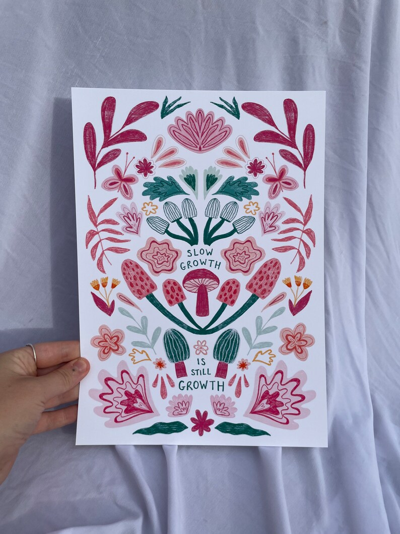Pu&ograve; includere: Una stampa floreale colorata con uno schema di colori verde, rosa e rosso. La stampa presenta funghi e il testo "Slow Growth is Still Growth".