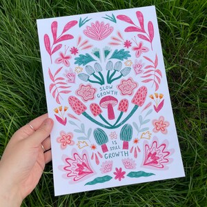 Pu&ograve; includere: Una stampa bianca con un design floreale rosa e verde. La stampa presenta il testo "Slow Growth is Still Growth".