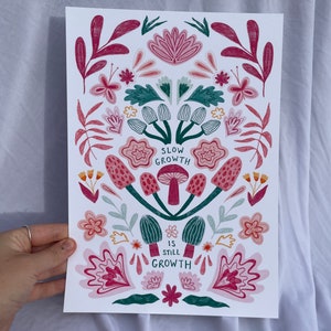 Pu&ograve; includere: Uno sfondo bianco con un design floreale rosa, verde e rosso. Il testo "Slow Growth is Still Growth" &egrave; al centro del design.
