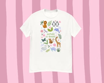 May include: White t-shirt with a colorful illustration of various animals, including a lion, penguins, and a giraffe. The text "NATURE IS QUEER" is printed in a playful font. The design features butterflies, flowers, and leaves.