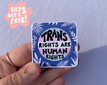 May include: A blue and white sticker with the text "Trans Rights Are Human Rights" in a circle with a pink, blue, and white transgender pride flag design. The sticker has a white border and is surrounded by white leaves on a blue background.