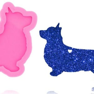 May include: Pink silicone mold shaped like a corgi with a small heart on the back. The mold is used to create a blue glitter corgi.