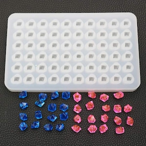 May include: A white silicone mold with 60 individual cavities shaped like diamonds. The mold is filled with blue and pink resin gems.