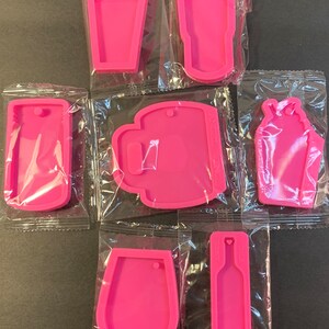 May include: Seven pink silicone molds for making resin crafts. The molds are shaped like a wine glass, a bottle, a mug, a shaker, and two different styles of tumblers.