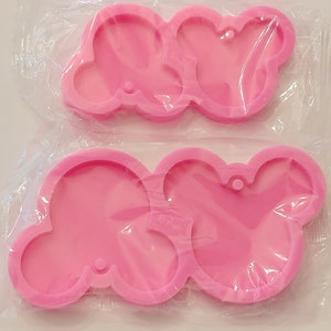 May include: Two pink silicone molds for making resin crafts. Each mold has three connected circles with a hole at the top.