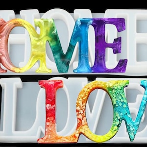 May include: A silicone mold for resin casting, featuring the words "HOME" and "LOVE" in a rainbow color scheme. The mold is designed to create colorful, decorative letters.