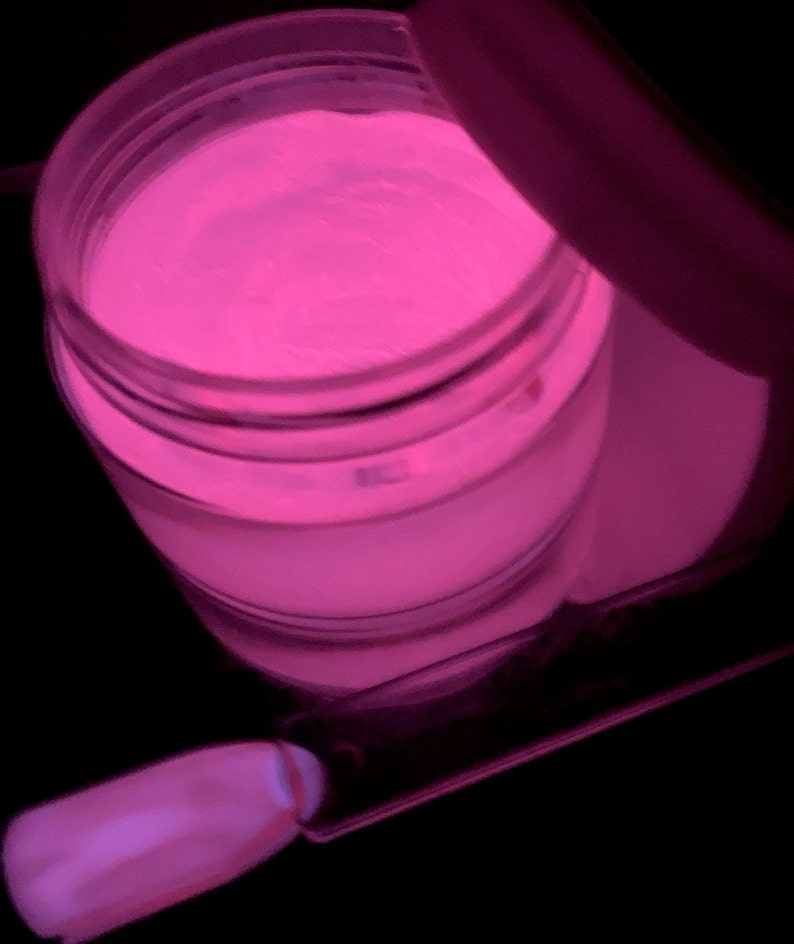 May include: A clear jar filled with a bright pink glow-in-the-dark powder. The powder is used for nail art and is shown with a small brush.