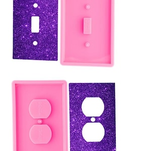 May include: Two rectangular light switch covers with a purple glitter finish and two corresponding pink silicone molds. One cover is for a single toggle switch, and the other is for a duplex outlet. The molds feature embossed text reading Angel Wings.