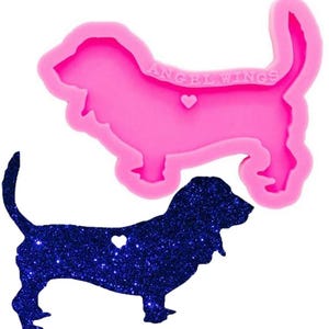 May include: Pink silicone mold of a basset hound with a heart cutout. The mold is labeled "Angel Wings". A blue glitter basset hound with a heart cutout is shown next to the mold.