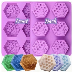 May include: A purple silicone mold with honeycomb-shaped cavities, each featuring a bee design. The mold is labeled "Front" and "Back". Below are six hexagonal soaps in various colors, including green, blue, and gold, showcasing the mold's potential.