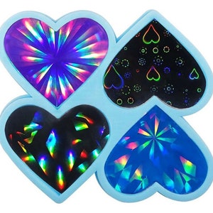 May include: Four iridescent heart-shaped stickers with different designs. The stickers are on a light blue background.