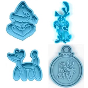 May include: Four light blue silicone molds in various shapes. One is a Grinch face, another a cartoon reindeer, a third a balloon dog, and the last a Christmas ornament with a couple embracing.