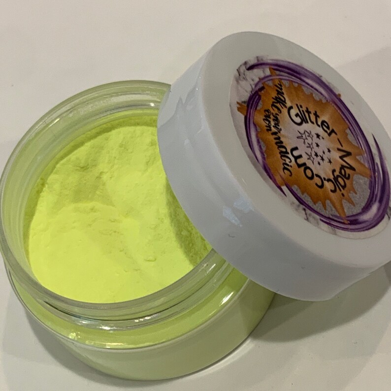 May include: A small jar of neon yellow glitter powder with a white lid. The lid has a purple and gold sticker with the text "Glitter Magic" and "Worn Magic" on it.