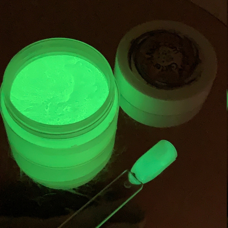 May include: A small jar of green glow-in-the-dark powder. The powder is in a clear jar with a white lid. A small sample of the powder is shown on a clear plastic stick.