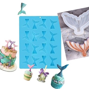 May include: A blue silicone mold with 18 mermaid tail shapes. The mold is next to a cake and cupcakes decorated with mermaid tails. The cake is two tiers and has a light blue and pink frosting. The cupcakes are topped with blue and pink frosting and mermaid tails.