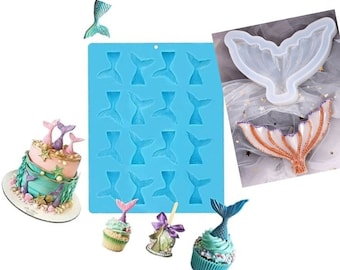 May include: A blue silicone mold with 18 mermaid tail shapes. The mold is next to a cake and cupcakes decorated with mermaid tails. The cake is two tiers and has a light blue and pink frosting. The cupcakes are topped with blue and pink frosting and mermaid tails.