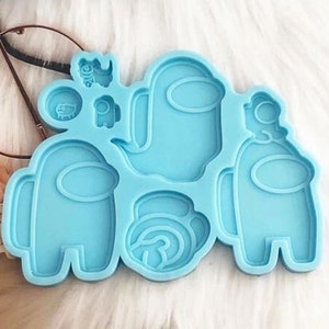 May include: Blue silicone mold with multiple shapes of the popular video game character Among Us. The mold includes a large crewmate, a smaller crewmate, a ghost, and a round object.