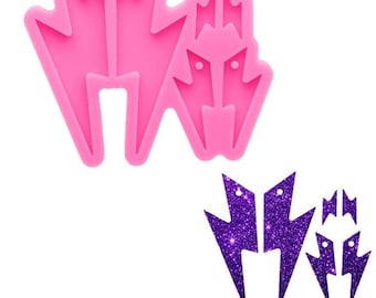 May include: Pink silicone mold with four lightning bolt shapes. The mold is used to create resin earrings. The mold is shown with purple glitter resin earrings.