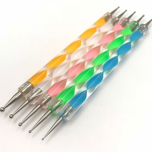 May include: Set of six colorful nail art tools with clear handles and silver metal tips. The handles have a spiral pattern with alternating colors of yellow, pink, green, and blue.