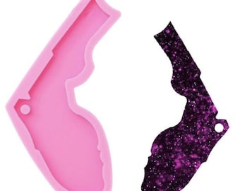 Könnte beinhalten: Eine rosa Silikonform und ein fertiges Harzteil. Die Form hat die Form eines Staates mit einem Griff. Das fertige Teil ist dunkelviolett mit Glitzer und einem Loch für einen Schlüsselanhänger.