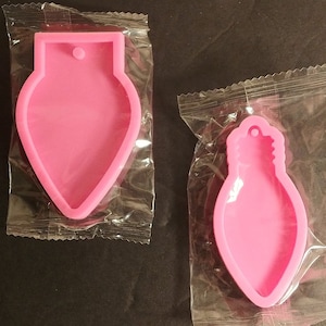 May include: Two pink silicone molds shaped like light bulbs. Each mold has a hole at the top for hanging.