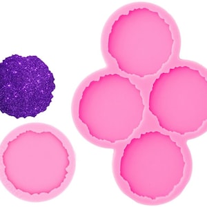 May include: Pink silicone mold with three round, slightly irregular shapes, resembling agate slices. The mold is designed for creating resin coasters or other decorative items.