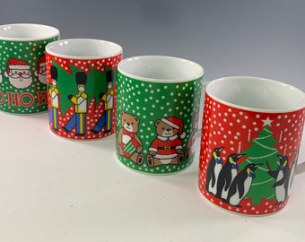 May include: Set of four white ceramic mugs with Christmas themed designs. The mugs feature Santa Claus, toy soldiers, teddy bears, and penguins.