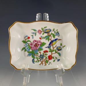 May include: A rectangular white porcelain dish with a gold rim. The dish is decorated with a colorful floral and bird design. The bird is blue, yellow, and green, perched on a branch with pink, blue, and red flowers.