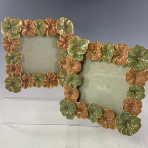 May include: Two ornate picture frames made of ceramic with a floral design. The frames are green, brown, and gold in color and feature a raised flower pattern.
