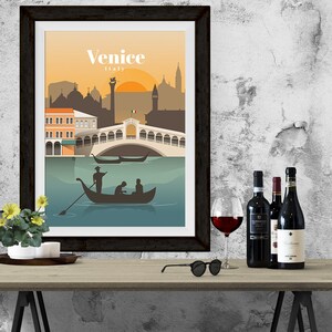 May include: A framed poster with a colorful illustration of Venice, Italy. The poster features a bridge, gondolas, and buildings. The text "Venice, Italy" is printed on the poster.