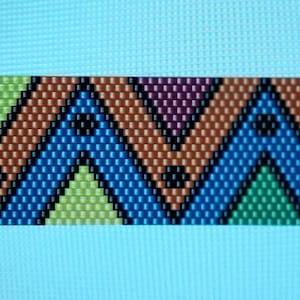 Può includere: Primo piano di un motivo di perline con un design a zig-zag. Il motivo presenta file alternate di perline marroni, verdi, blu e viola. Piccole perline nere sono sparse nel design.