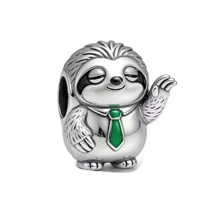 May include: A silver-colored charm in the shape of a sloth wearing a green tie. The sloth has black eyes and a smiling expression, with one arm raised in a wave. The charm is detailed with textured fur and a small hole for threading.