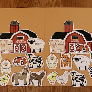 Op de afbeelding: Een bruine kartonnen map met twee rode schuren aan de voorkant. De schuren hebben witte ramen en deuren. De map is verdeeld in twee secties, een met het label "Adjectieven" en de andere met het label "Bijwoorden". Er zijn verschillende dier- en woordkaarten verspreid rond de schuren. De woorden omvatten "zoet", "onhandig", "bijna", "slaperig", "fancy", "rond", "schoon", "luid", "spoedig", "binnen", "langzaam", "onder", "snel", "vrolijk", "voorzichtig", "boos", "nu", "nooit", "vandaag", en "weg".