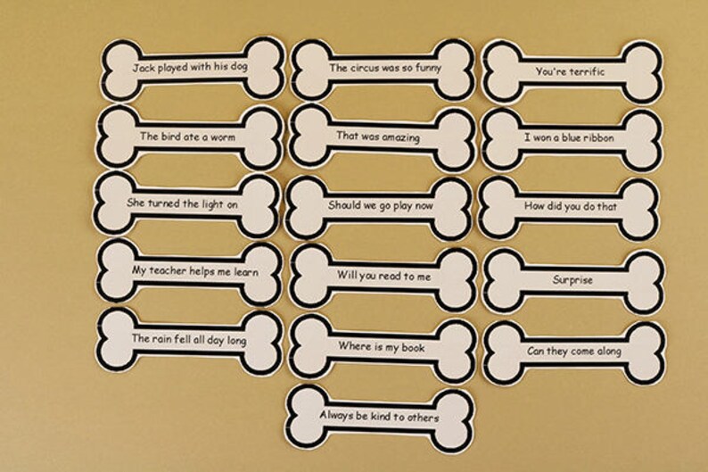 Pu&ograve; includere: Un set di 15 carte bianche a forma di osso con contorni neri. Ogni carta ha una frase diversa scritta in nero. Le frasi sono: "Jack ha giocato con il suo cane", "Il circo era cos&igrave; divertente", "Sei fantastico", "L'uccello ha mangiato un verme", "&Egrave; stato fantastico", "Ho vinto un nastro blu", "Ha acceso la luce", "Dovremmo andare a giocare ora", "Come hai fatto?", "Il mio insegnante mi aiuta a imparare", "Mi leggerai?", "Sorpresa", "La pioggia &egrave; caduta tutto il giorno", "Dove &egrave; il mio libro?", "Possono venire?", e "Sii sempre gentile con gli altri".
