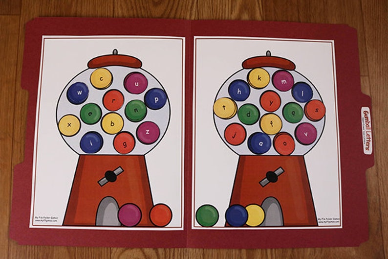 May include: A red folder with two gumball machines on the front. Each gumball machine has a different set of letters inside. The letters are in different colors. The folder has the words "Gumball Letters" on the front.