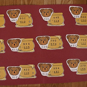 May include: A red felt board with 12 honey pot and bear cutouts. Each cutout has a subtraction problem with the answer written below. The problems are all single-digit subtraction problems.