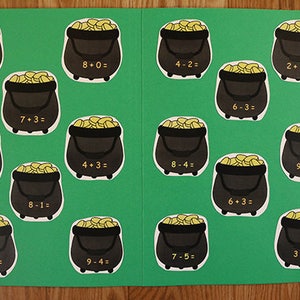 May include: A green folder with 16 gold coin pots with math problems written on them. The problems are addition and subtraction problems. The text on the folder says "Counting My Gold".