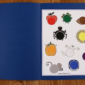 May include: A blue folder with a white sheet inside. The sheet has various black and white outlines of objects with blank circles in the middle. The objects include an apple, a leaf, an eye, a spider, a sunflower, a pumpkin, a ghost, a mouse, a helmet, and a bell. The text "Color Match" is on the tab of the folder.