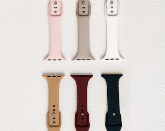 Könnte beinhalten: Sechs Uhrenarmbänder in verschiedenen Farben: Rosa, Beige, Weiß, Hellbraun, Burgunderrot und Marineblau. Jedes Band hat eine Schnalle und mehrere Verstelllöcher. Die Bänder sind auf einer strukturierten weißen Oberfläche dargestellt.