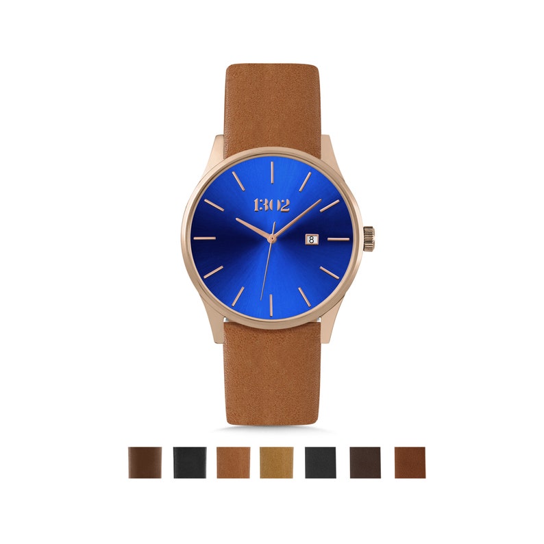 K&ouml;nnte beinhalten: Eine ros&eacute;goldene Uhr mit blauem Zifferblatt und braunem Lederarmband. Das Zifferblatt der Uhr hat ein Datumsfenster und den Markennamen "1302" aufgedruckt.