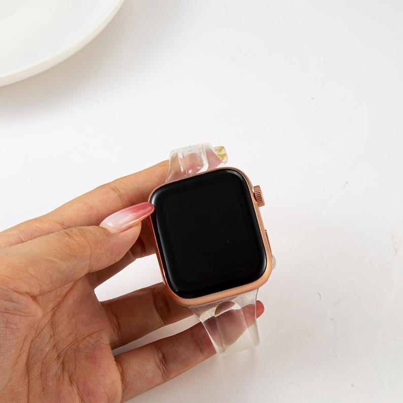 K&ouml;nnte beinhalten: Ein klares, transparentes Armband mit einem ros&eacute;goldenen Apple Watch-Zifferblatt.