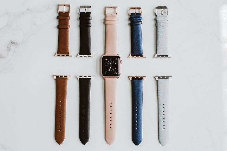 Puede incluir: Un conjunto de siete correas de reloj de cuero en varios colores, incluyendo marr&oacute;n, negro, rosa, azul y gris. Las correas est&aacute;n dispuestas en dos filas, con una esfera de reloj en el centro.