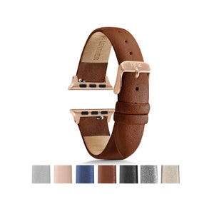 Puede incluir: Una correa de reloj de cuero marr&oacute;n con una hebilla de oro rosa y una etiqueta "LEATHER". La correa es compatible con Apple Watch.