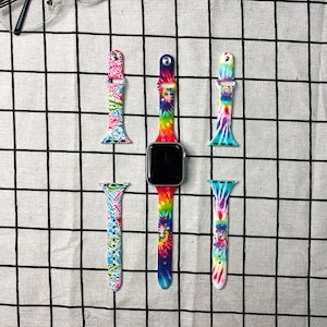 Puede incluir: Cuatro bandas de Apple Watch de color tie-dye. Dos bandas son cortas y dos son largas. Las bandas largas est&aacute;n unidas a un Apple Watch plateado.