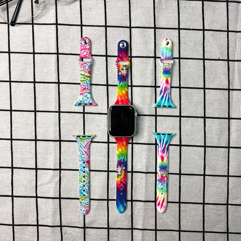Puede incluir: Cuatro bandas de Apple Watch de color tie-dye. Dos bandas son cortas y dos son largas. Las bandas largas est&aacute;n unidas a un Apple Watch plateado.