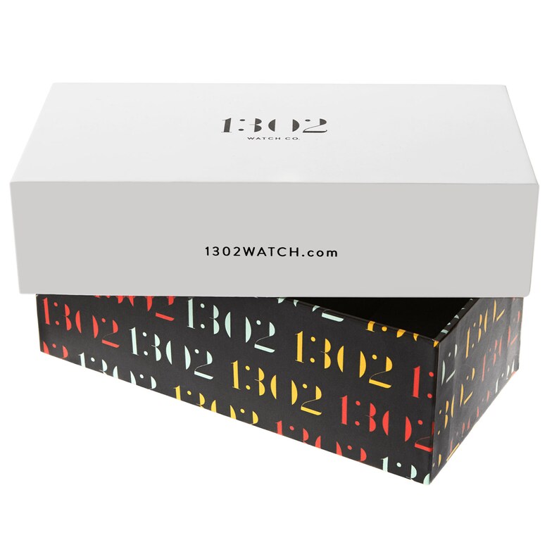 K&ouml;nnte beinhalten: Eine wei&szlig;e Box mit dem Text "1302 WATCH CO." und "1302WATCH.com" darauf gedruckt. Die Box ist ge&ouml;ffnet und das Innere ist mit schwarzem Papier ausgekleidet, das ein sich wiederholendes Muster des Textes "1302" in verschiedenen Farben aufweist.