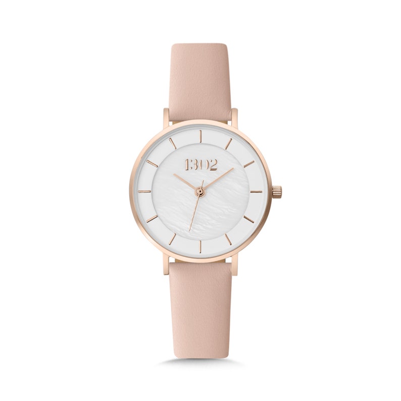 May include: A rose gold watch with a white face and a pink leather band. The watch face has a white mother-of-pearl texture and the brand name "1302" is printed on the face.