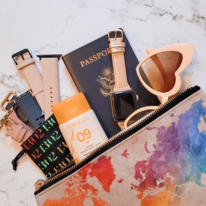 Pu&ograve; includere: Un kit di accessori da viaggio con un passaporto, occhiali da sole, un orologio, crema solare e una piccola borsa con un design a mappa del mondo. La bottiglia di crema solare riporta "SPF 09 (80 min)" e "Resistente al sudore e all'acqua".