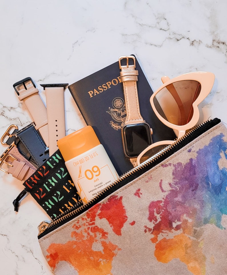 Pu&ograve; includere: Un kit di accessori da viaggio con un passaporto, occhiali da sole, un orologio, crema solare e una piccola borsa con un design a mappa del mondo. La bottiglia di crema solare riporta "SPF 09 (80 min)" e "Resistente al sudore e all'acqua".